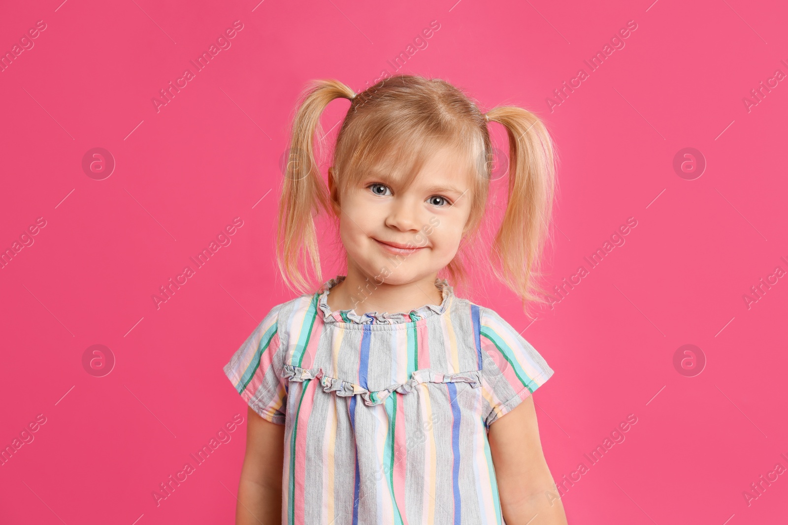 Photo of Portrait of cute little girl on pink background