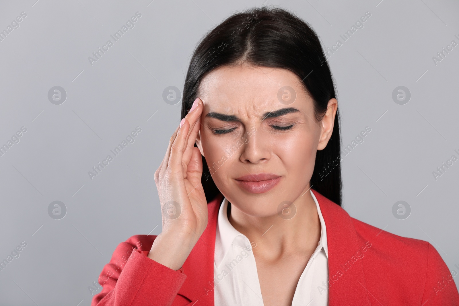 Photo of Woman suffering from migraine on grey background