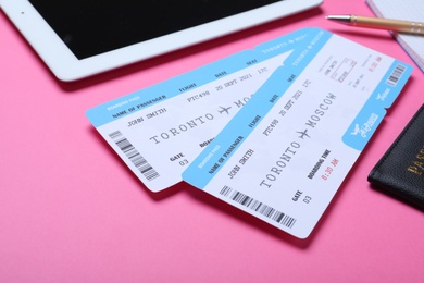 Photo of Tickets, passport and tablet on pink background. Travel agency concept