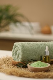 Photo of Spa composition. Rolled towel, cosmetic product, sea salt and twig on table indoors. Space for text