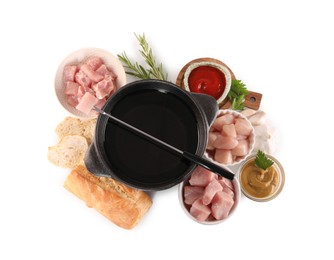 Photo of Fondue pot with oil, fork, raw meat pieces and other products isolated on white, top view