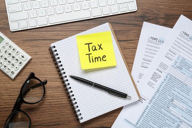 Reminder note with words Tax Time, documents, computer keyboard and calculator on wooden table, flat lay