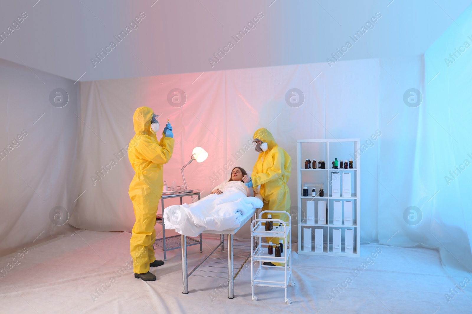 Photo of Paramedics wearing protective suits examining patient with virus in quarantine ward