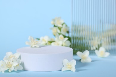 Photo of Presentation of product. White podium and beautiful jasmine flowers on light blue background, closeup