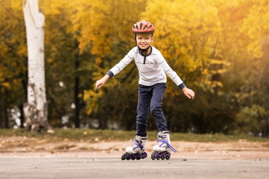 Photo of Happy boy roller skating in autumn park