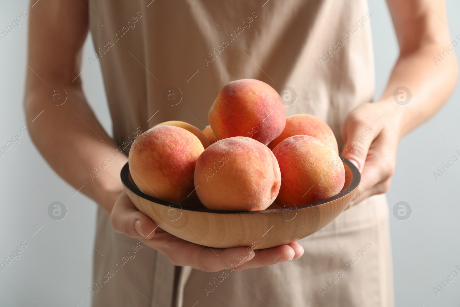 Photo of Woman holding plate with fresh sweet peaches, closeup