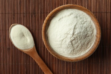 Bowl and spoon of agar-agar powder on bamboo mat, flat lay