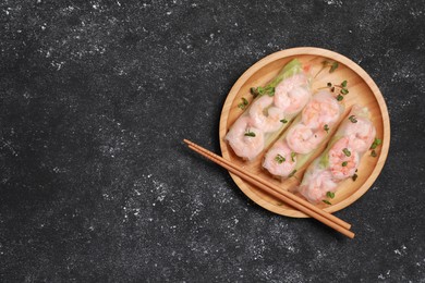 Photo of Plate with tasty spring rolls, microgreens and chopsticks on grey textured table, top view. Space for text