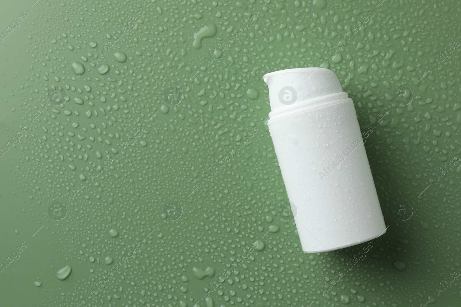 Photo of Moisturizing cream in bottle on green background with water drops, top view. Space for text