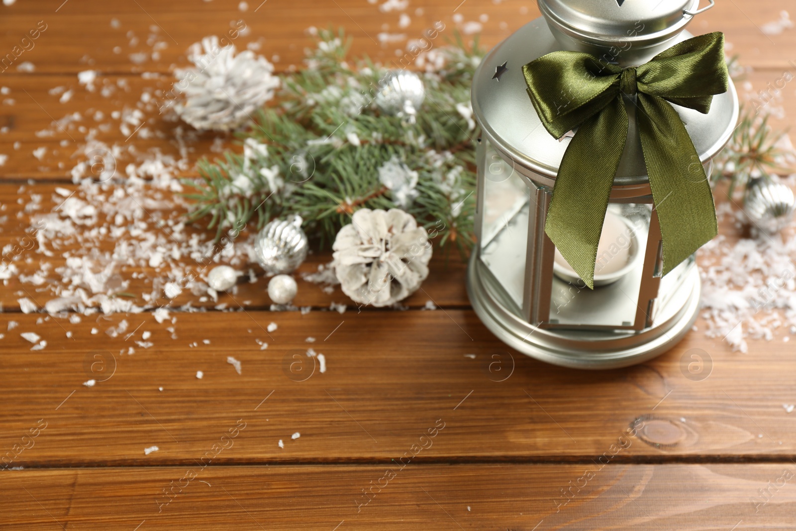 Photo of Christmas lantern with burning candle and festive decor on wooden table. Space for text