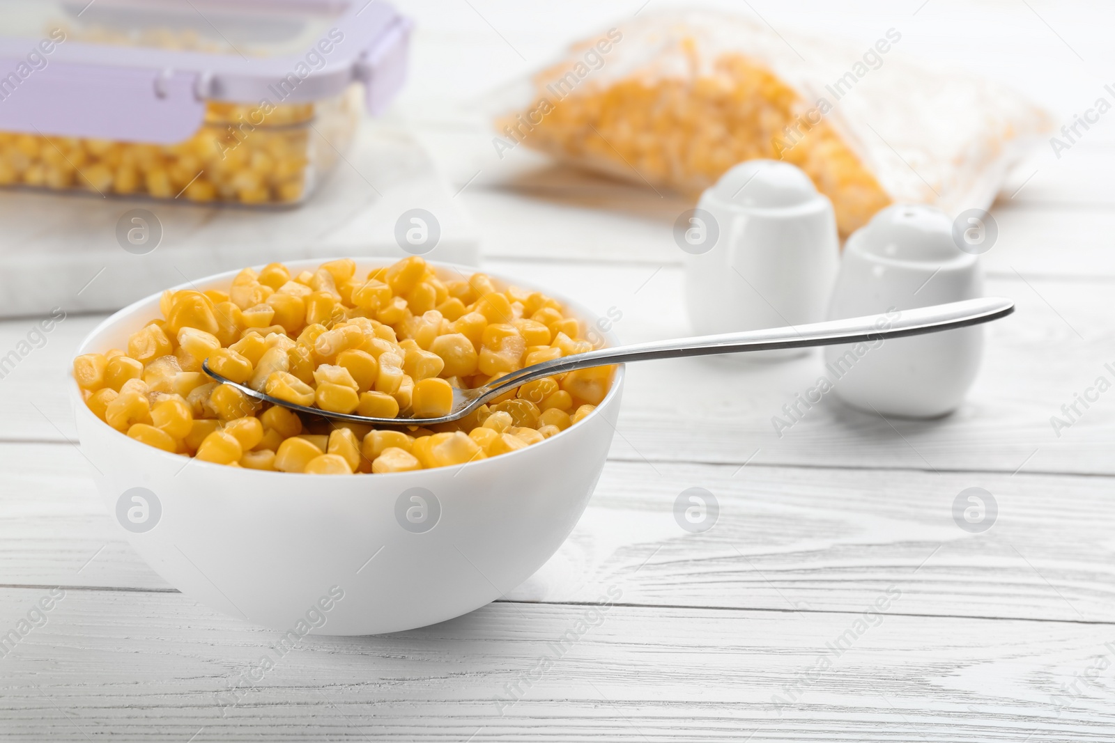 Photo of Frozen sweet corn on white wooden table. Vegetable preservation