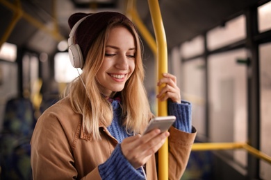 Photo of Young woman with headphones listening to music in public transport
