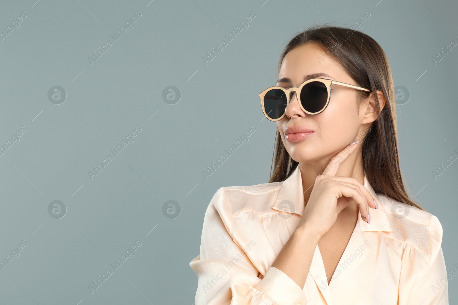 Photo of Beautiful young woman wearing sunglasses on grey background. Space for text