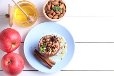 Tasty baked apple with nuts, honey, spices and mint on white wooden table, flat lay. Space for text