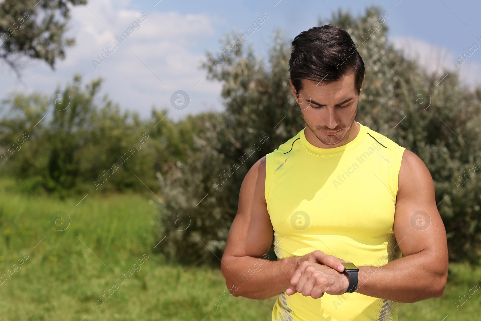 Photo of Young man checking pulse with smartwatch after training in park. Space for text