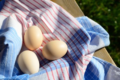 Photo of Raw duck eggs with napkin on wooden table outdoors