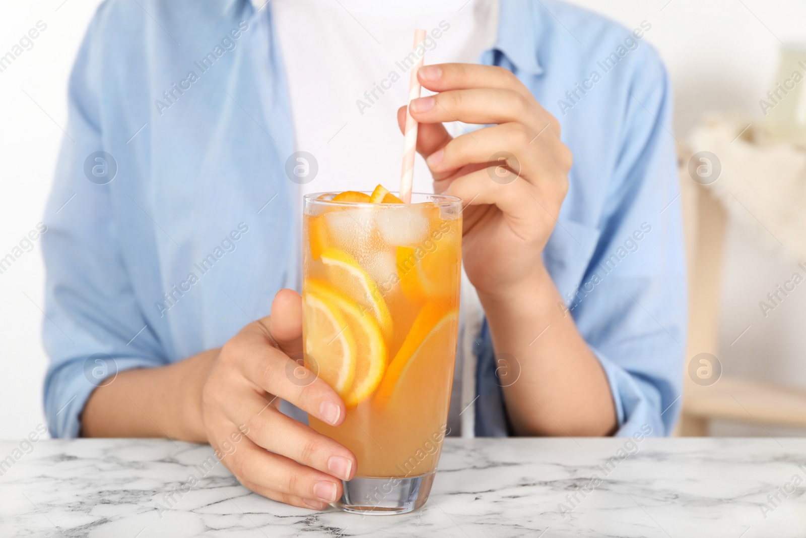 Photo of Woman with glass of orange refreshing drink at marble table, closeup