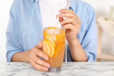 Photo of Woman with glass of orange refreshing drink at marble table, closeup