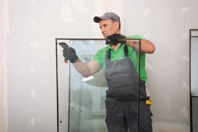 Photo of Worker in uniform preparing double glazing window for installation indoors