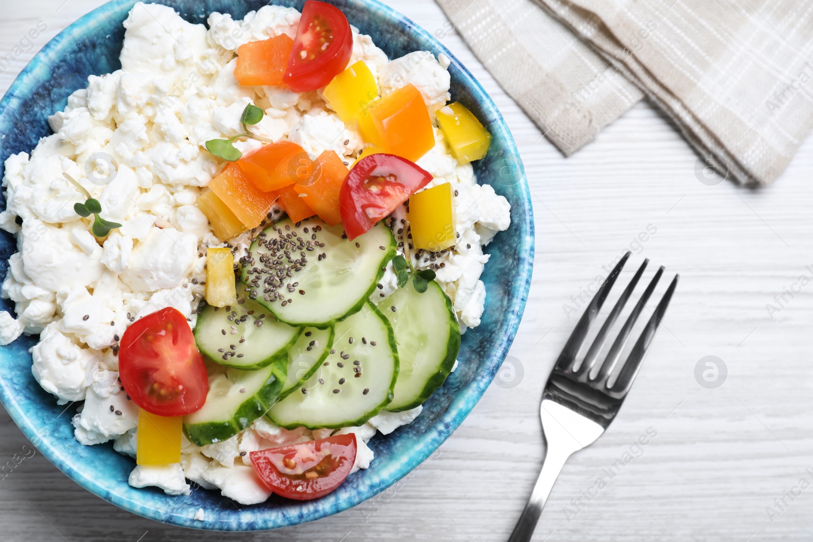 Photo of Delicious cottage cheese with vegetables and chia seeds served for breakfast on white wooden table, flat lay