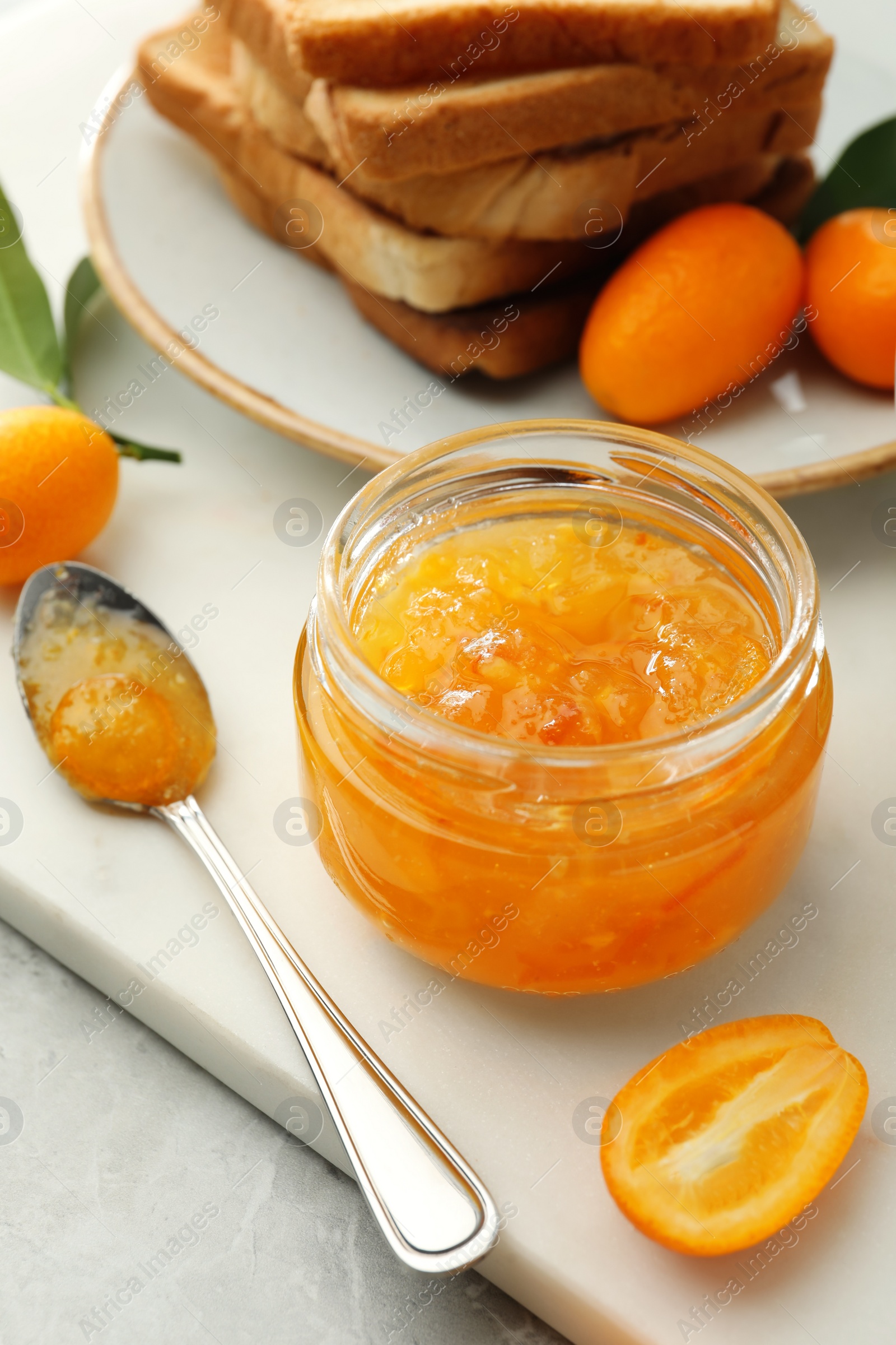Photo of Delicious kumquat jam, fresh fruits and bread on white board