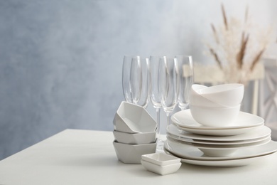 Photo of Set of clean dishware and champagne glasses on white table indoors. Space for text