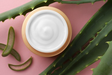 Photo of Jar with cream and cut aloe leaves on pink background, flat lay