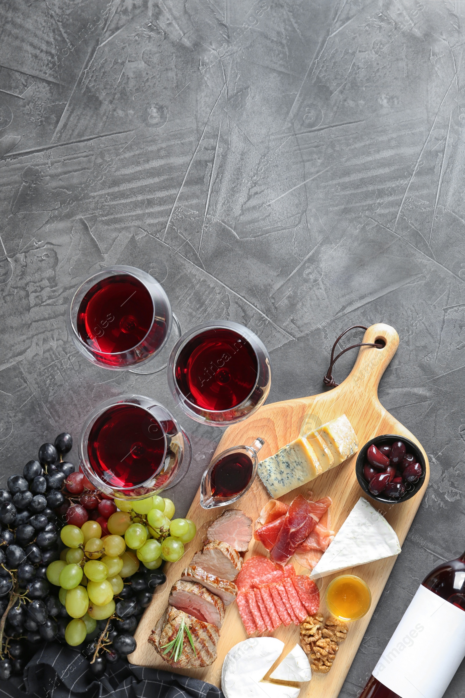 Photo of Flat lay composition with wine, snacks and space for text on grey background