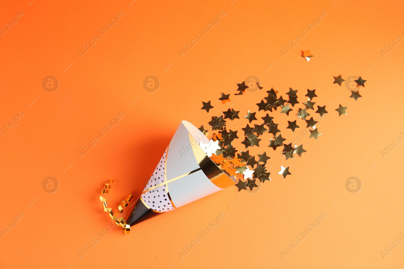 Photo of Party hat and confetti on orange background, top view