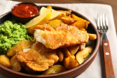 Photo of Plate with British traditional fish and potato chips on table, closeup