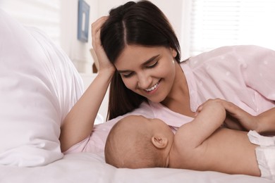 Happy young mother with her cute baby on bed at home