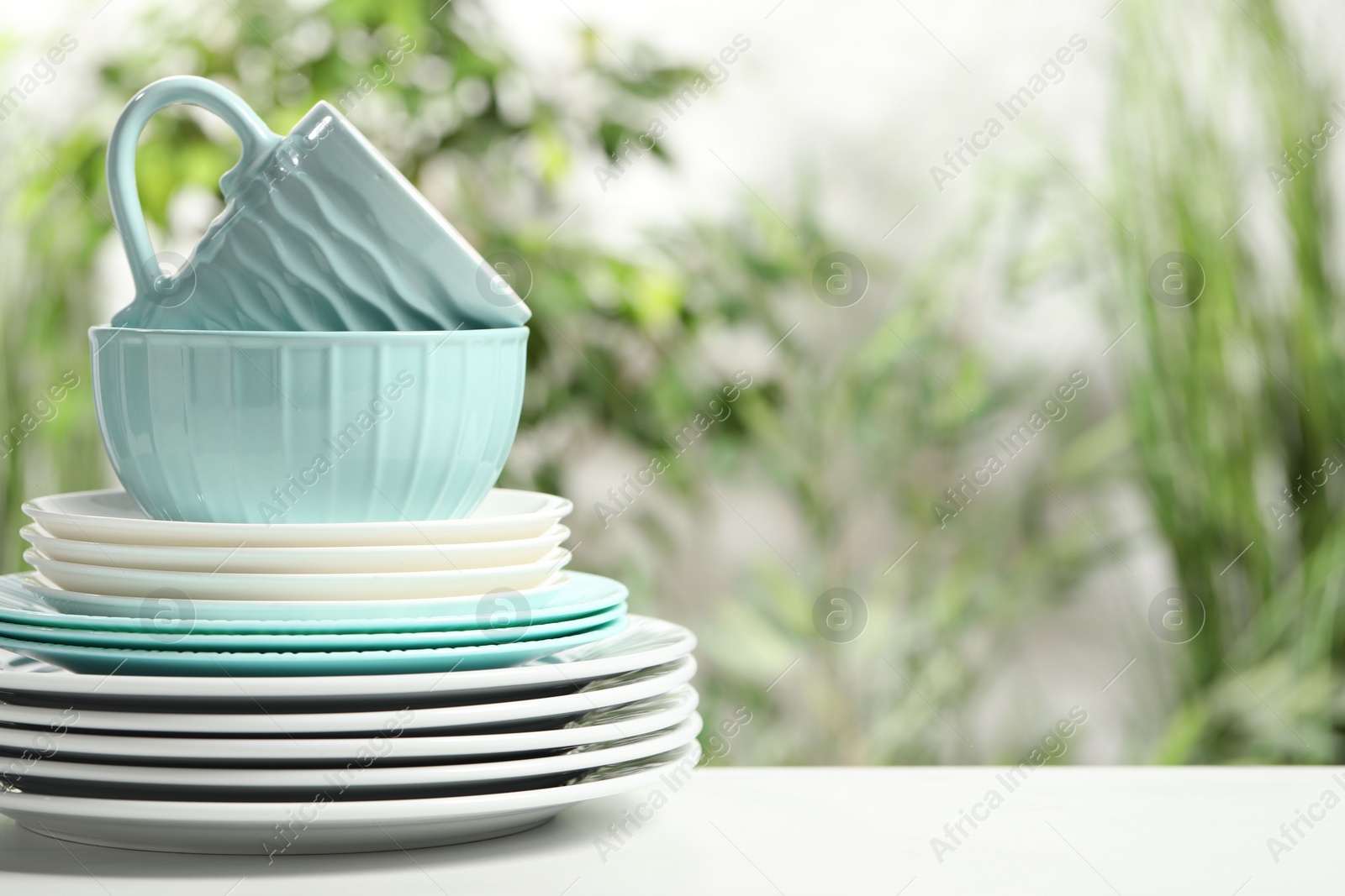 Photo of Beautiful ceramic dishware and cup on white table outdoors, space for text