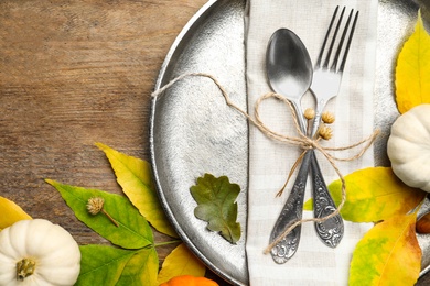 Seasonal table setting with pumpkins and other autumn decor on wooden background, flat lay