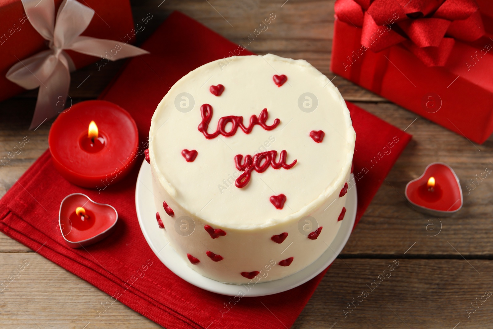 Photo of Bento cake with text Love You, candles and gift boxes on wooden table. St. Valentine's day surprise