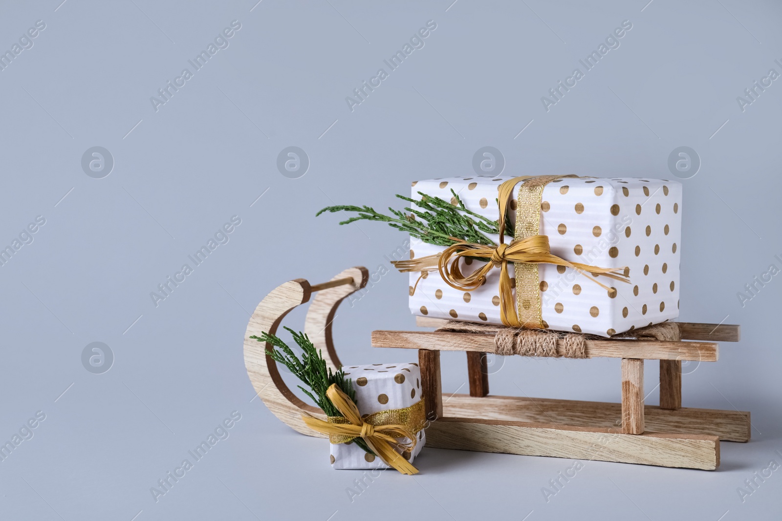 Photo of Wooden sleigh with gift boxes on light grey background. Space for text
