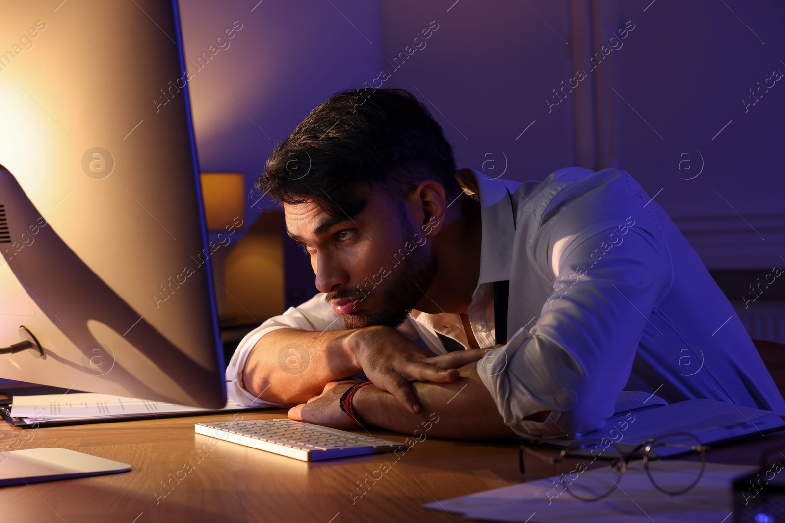 Photo of Tired young man working late in office