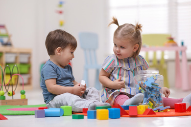 Cute little children playing together on floor at home