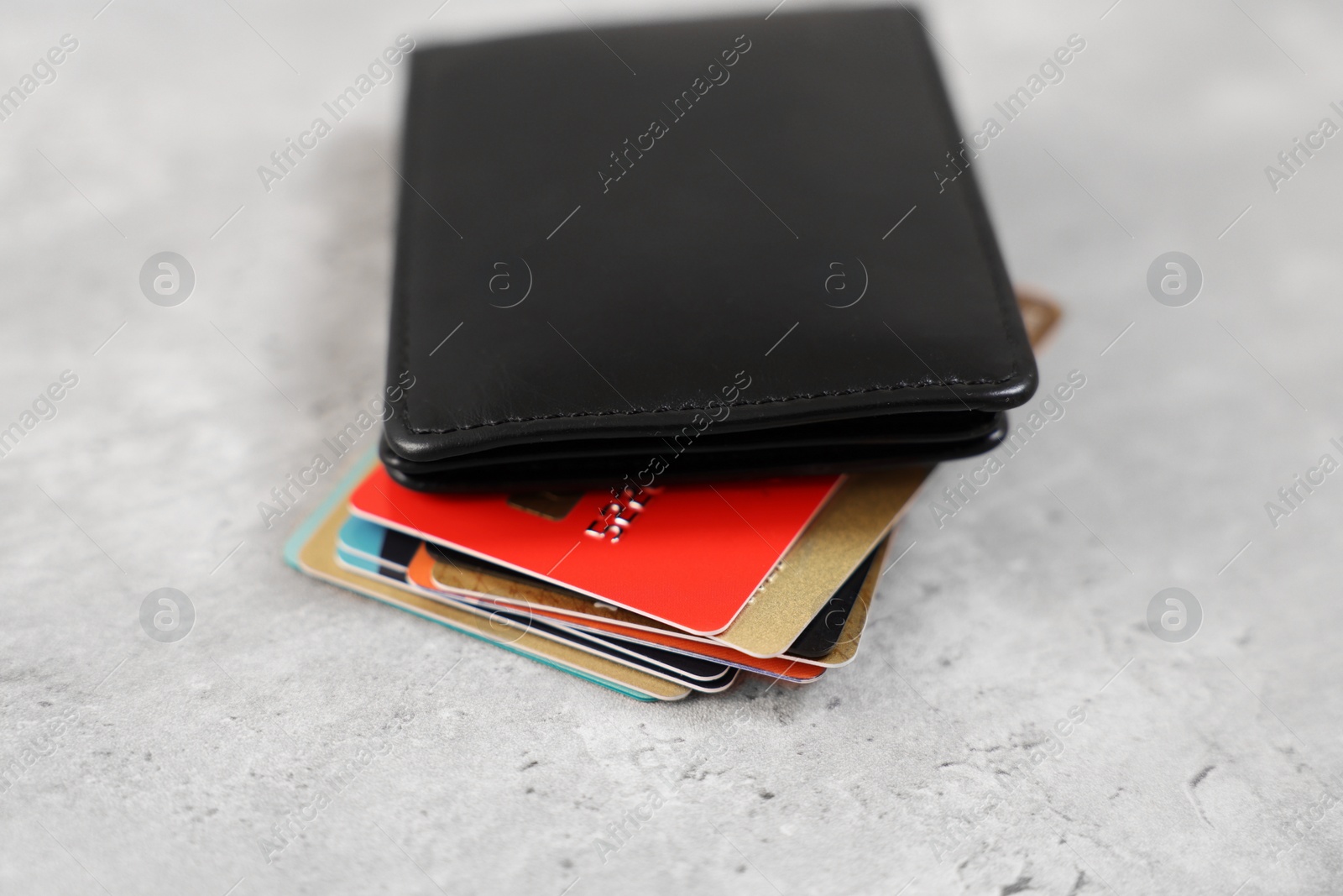 Photo of Many different credit cards and leather wallet on grey table, closeup