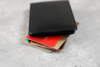 Photo of Many different credit cards and leather wallet on grey table, closeup