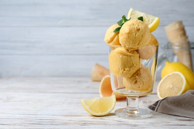 Photo of Yummy lemon ice cream served on white wooden table, space for text