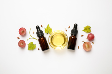 Photo of Composition with bottles and bowl of natural grape seed oil on white background, top view. Organic cosmetic