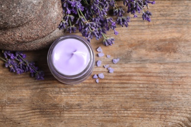 Stones, jar of cream and lavender flowers on wooden table, flat lay. Space for text