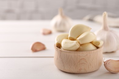 Fresh garlic on white wooden table, closeup. Space for text