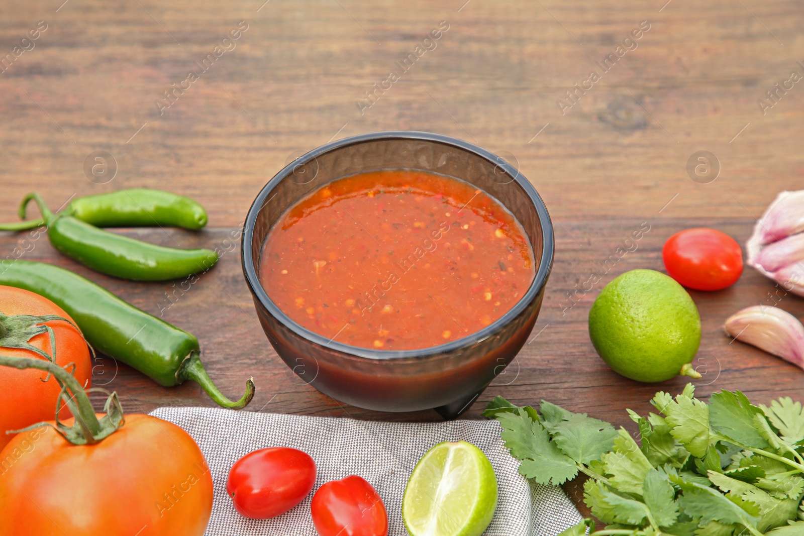 Photo of Tasty salsa sauce and different ingredients on wooden table