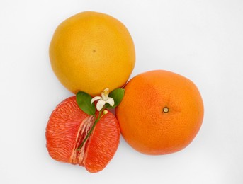 Fresh grapefruits and green leaves on white background, top view