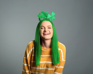 Image of St. Patrick's day party. Pretty woman with green hair and clover headband on grey background