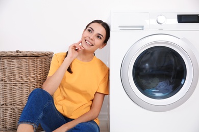 Young woman near washing machine at home. Laundry day