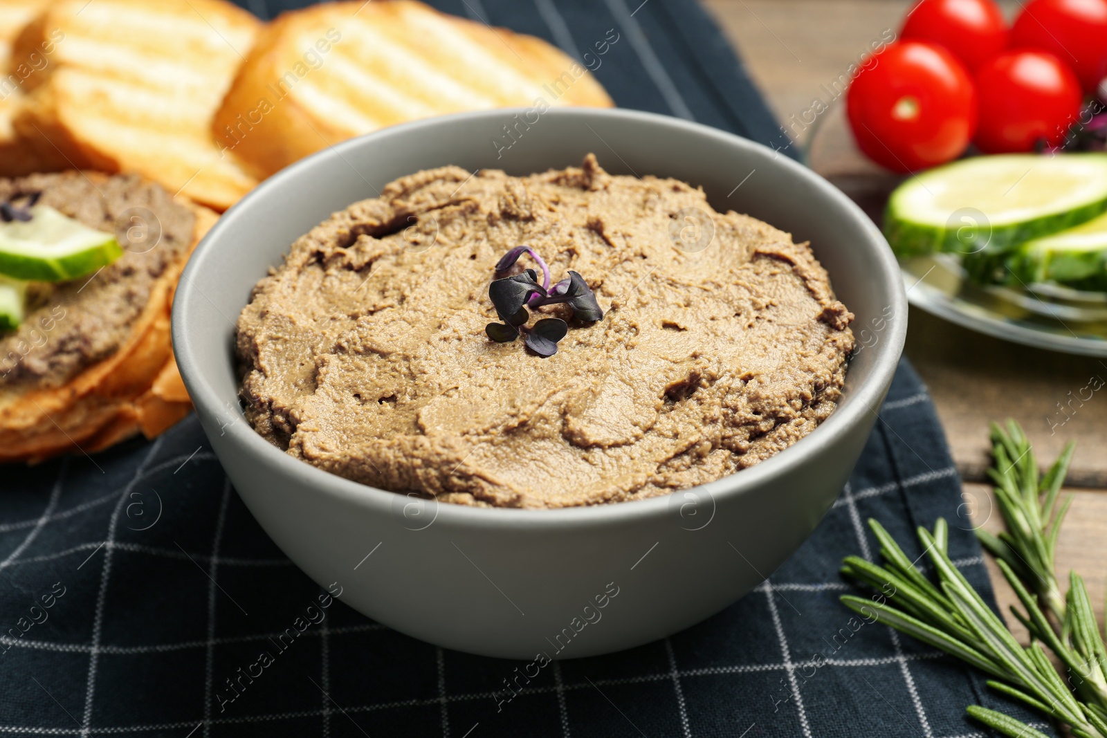 Photo of Bowl with delicious liver pate on wooden table, closeup