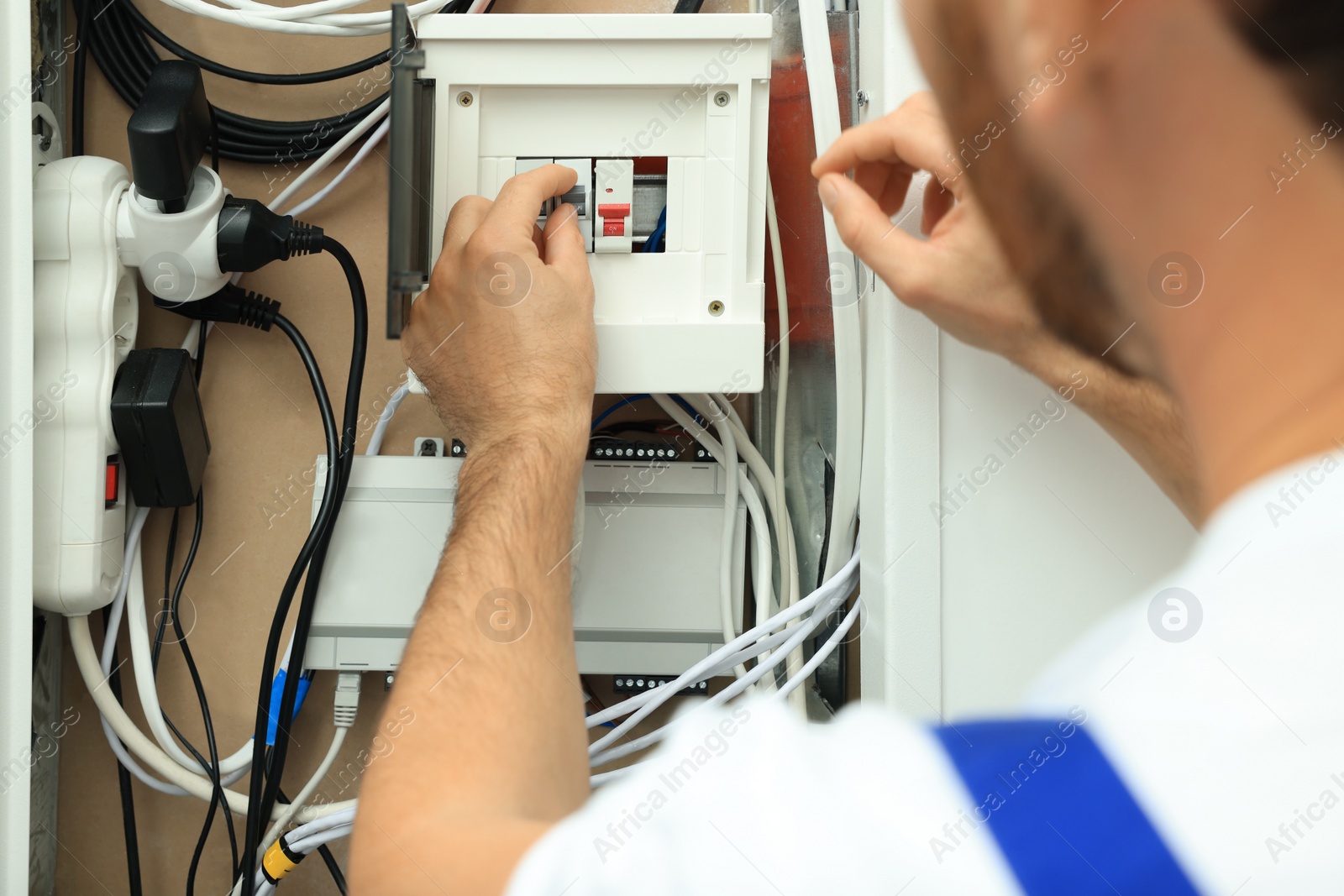 Photo of Electrician switching off circuit breakers in fuse box, closeup