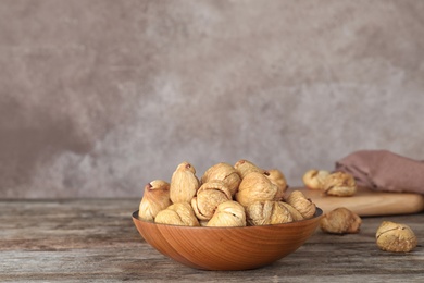 Photo of Wooden bowl with dried figs on table, space for text. Healthy fruit
